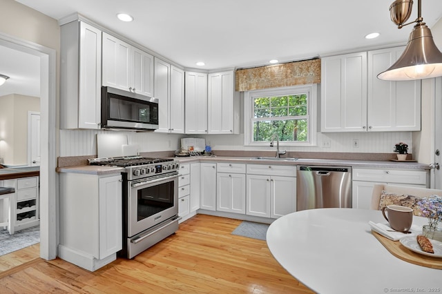 49 Bear Hills Rd, Newtown, CT 06470 - kitchen with stainless steel appliances, light wood finished floors, white cabinets, light countertops, and pendant lighting