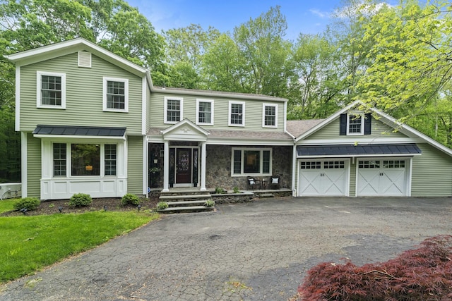 8A Russett Rd, Newtown, CT 06482 - view of front of house featuring asphalt driveway, a standing seam roof, an attached garage, metal roof, and covered porch