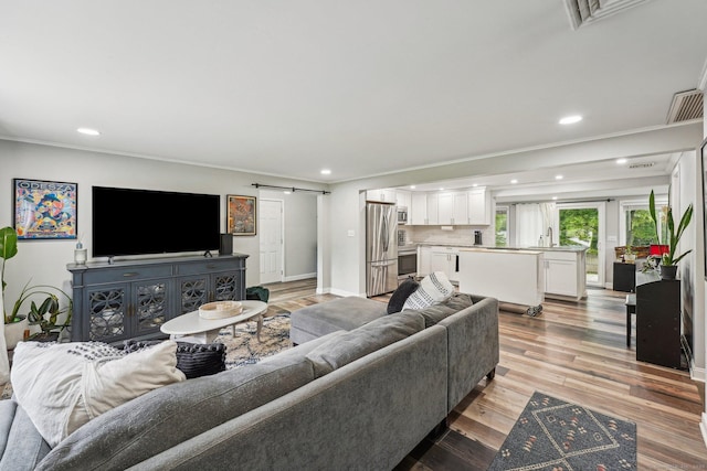 288 Robbins Ave, Newington, CT 06111 - living room featuring a barn door, recessed lighting, crown molding, light wood-type flooring, and baseboards