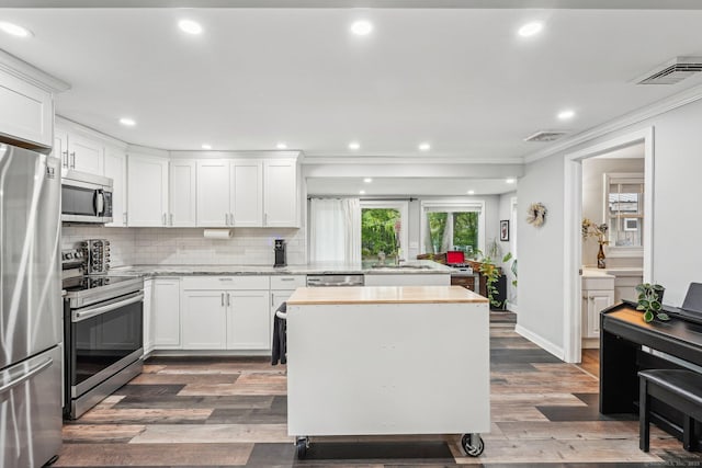288 Robbins Ave, Newington, CT 06111 - kitchen featuring appliances with stainless steel finishes, ornamental molding, white cabinets, wood finished floors, and recessed lighting