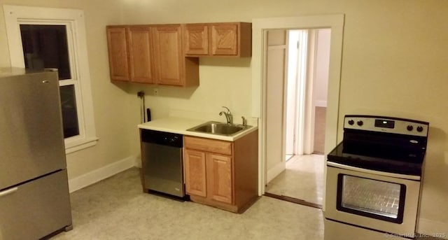 kitchen featuring a sink, stainless steel appliances, light countertops, and brown cabinetry