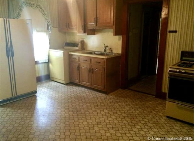 kitchen featuring washer / dryer, range with gas stovetop, a sink, freestanding refrigerator, and light countertops