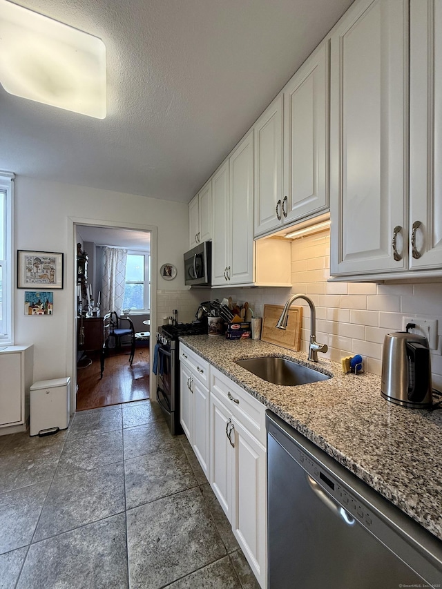 1 Strawberry Hill Ct Apt 6F, Stamford, CT 06902 - kitchen featuring a sink, stainless steel appliances, white cabinetry, tasteful backsplash, and a textured ceiling