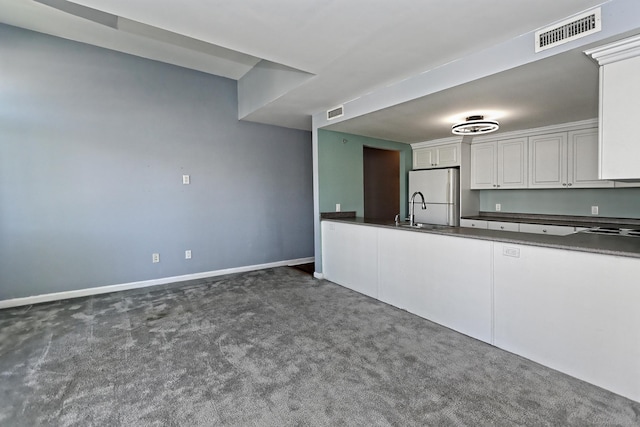 3250 Fairfield Ave Apt 302, Bridgeport, CT 06605 - kitchen featuring freestanding refrigerator, dark countertops, dark colored carpet, and white cabinets