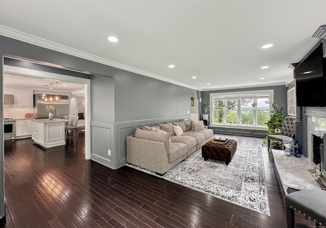 130 Wildewood Run, Bristol, CT 06010 - living area with crown molding, dark wood-type flooring, a premium fireplace, a wainscoted wall, and recessed lighting