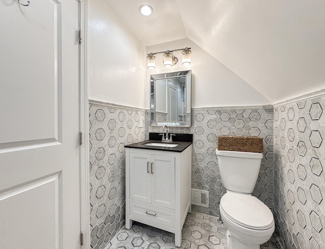 130 Wildewood Run, Bristol, CT 06010 - half bathroom featuring lofted ceiling, vanity, toilet, wainscoting, and tile walls