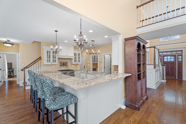 24 N Racebrook Rd, Woodbridge, CT 06525 - kitchen featuring stainless steel range with gas cooktop, dark wood-type flooring, a chandelier, tasteful backsplash, and white cabinetry