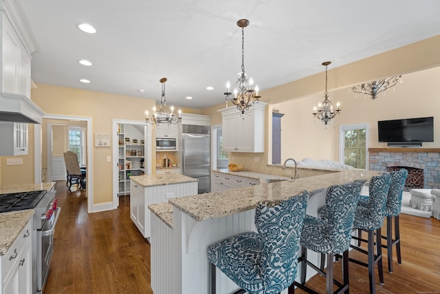 24 N Racebrook Rd, Woodbridge, CT 06525 - kitchen featuring built in appliances, a chandelier, dark wood finished floors, recessed lighting, and a stone fireplace