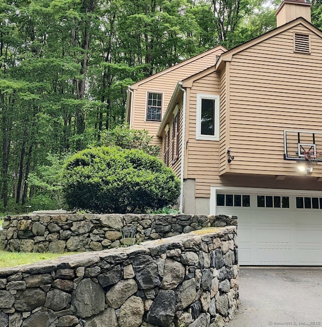 15 Packer Brook Rd, Redding, CT 06896 - view of side of property with asphalt driveway, a garage, and a chimney