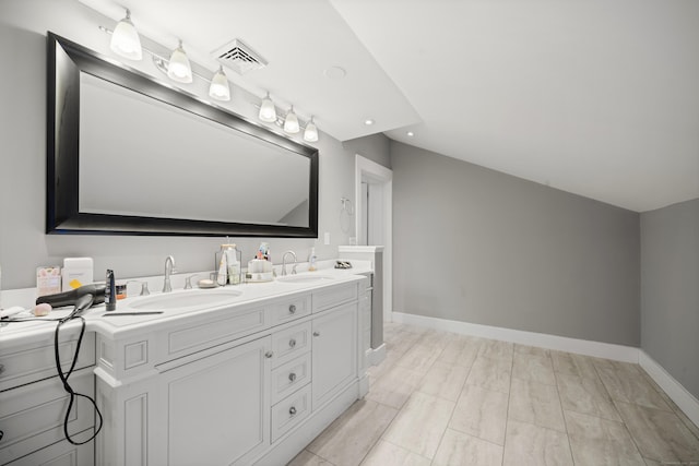bathroom with vaulted ceiling, recessed lighting, double vanity, and baseboards
