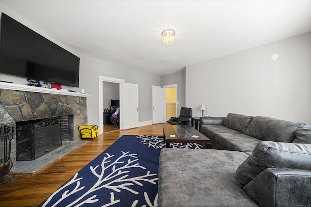 living area featuring a stone fireplace, wood finished floors, and baseboards