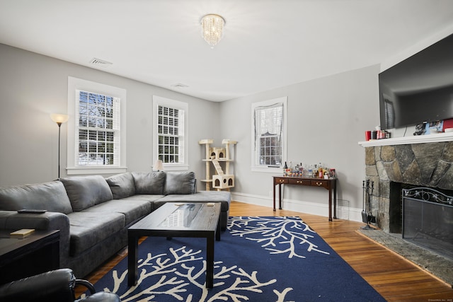 living area with a fireplace, wood finished floors, healthy amount of natural light, and baseboards