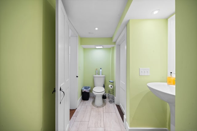 bathroom featuring toilet, baseboards, and recessed lighting