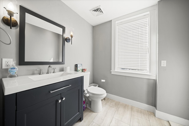 bathroom featuring baseboards, toilet, and vanity
