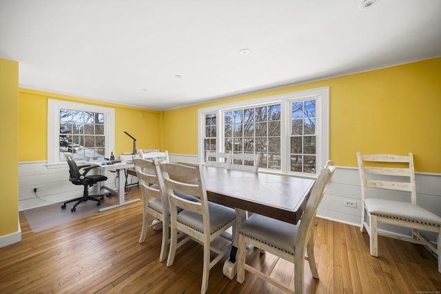 dining space with wainscoting, wood finished floors, and an office area