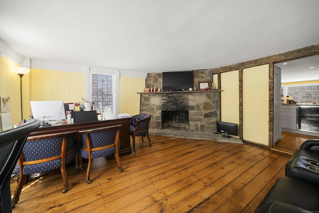 office area with beverage cooler, hardwood / wood-style floors, and a fireplace