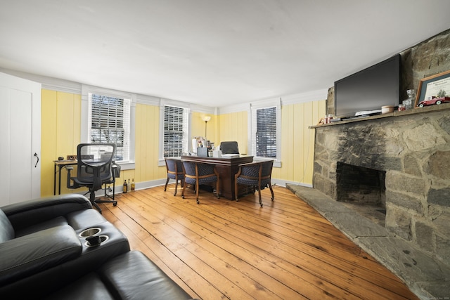 living area featuring light wood-style flooring and a stone fireplace