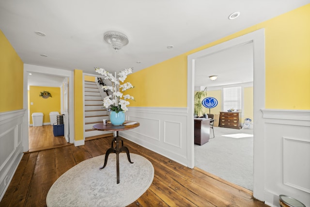 hallway with hardwood / wood-style flooring, wainscoting, stairway, and recessed lighting