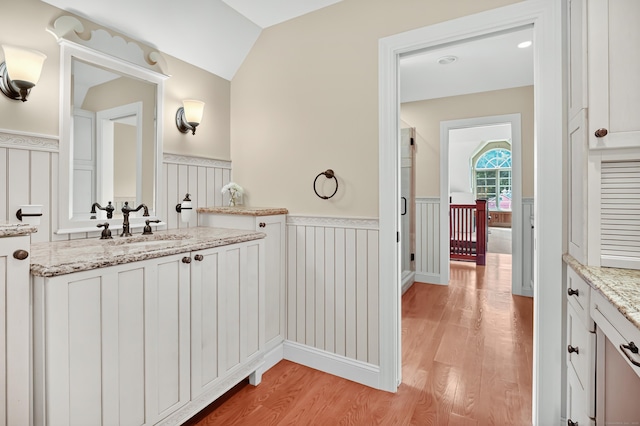 207 Great Pond Rd, Simsbury, CT 06070 - bathroom with wainscoting, wood finished floors, vaulted ceiling, vanity, and a decorative wall