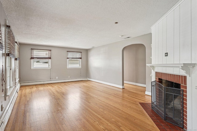81 Edward St, Newington, CT 06111 - unfurnished living room featuring a baseboard heating unit, a fireplace, hardwood / wood-style flooring, a textured ceiling, and arched walkways