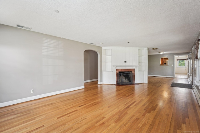 81 Edward St, Newington, CT 06111 - unfurnished living room featuring arched walkways, baseboards, a textured ceiling, and light wood-style floors