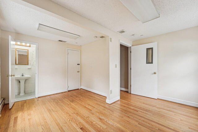 81 Edward St, Newington, CT 06111 - unfurnished bedroom featuring light wood-style floors, a textured ceiling, a sink, ensuite bath, and baseboards