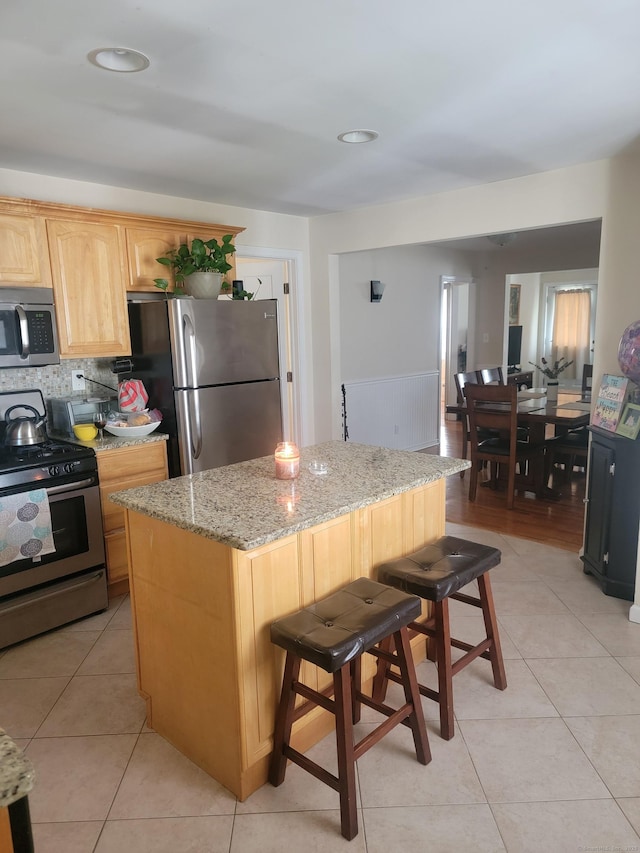 725 Merritt St, Bridgeport, CT 06606 - kitchen featuring stainless steel appliances, light tile patterned floors, light brown cabinets, a center island, and light stone countertops