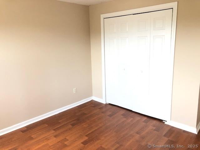452 Judd Sq Unit 452, Wallingford, CT 06492 - unfurnished bedroom with dark wood finished floors, a closet, and baseboards