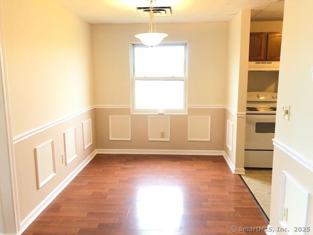 452 Judd Sq Unit 452, Wallingford, CT 06492 - unfurnished dining area featuring light wood-style floors and wainscoting
