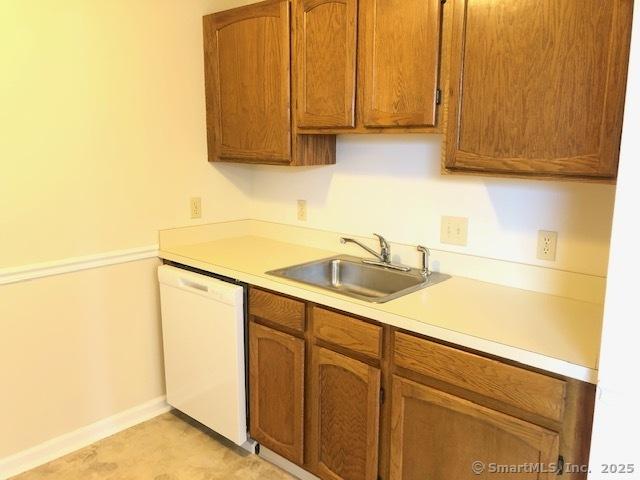 452 Judd Sq Unit 452, Wallingford, CT 06492 - kitchen with a sink, white dishwasher, light countertops, brown cabinetry, and baseboards