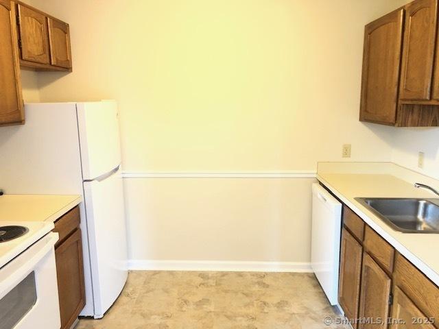 452 Judd Sq Unit 452, Wallingford, CT 06492 - kitchen featuring white appliances, a sink, brown cabinetry, and baseboards