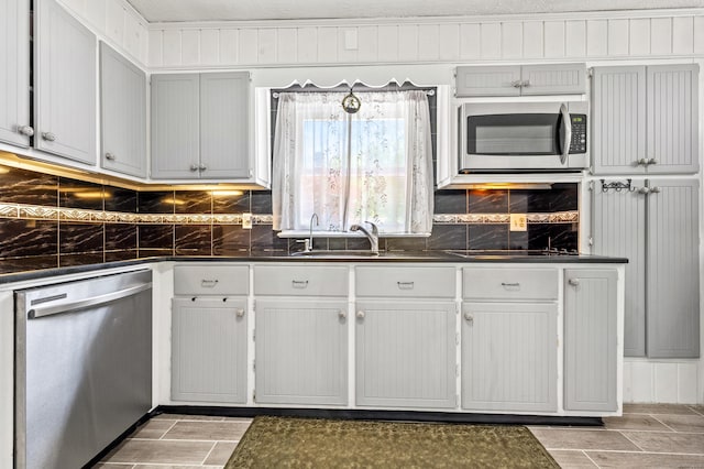 54 Swampscott Rd, Stamford, CT 06905 - kitchen with appliances with stainless steel finishes, dark countertops, a sink, backsplash, and wood finish floors