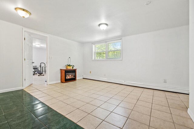 54 Swampscott Rd, Stamford, CT 06905 - empty room with a baseboard heating unit, light tile patterned floors, baseboards, and a glass covered fireplace