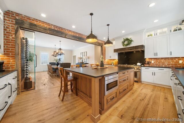 879 Russell Ave, Suffield, CT 06078 - kitchen with dark countertops, under cabinet range hood, light wood-style floors, backsplash, and recessed lighting