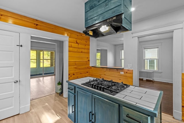 593 Cooke St, Waterbury, CT 06710 - kitchen with tile counters, black gas cooktop, radiator, under cabinet range hood, and plenty of natural light