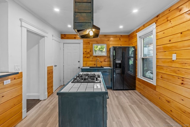 593 Cooke St, Waterbury, CT 06710 - kitchen featuring black fridge with ice dispenser, stainless steel gas stovetop, light wood-style floors, wood walls, and a sink