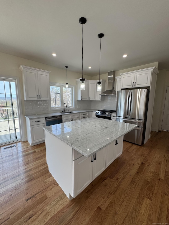 490 Lazy Ln, Southington, CT 06489 - kitchen featuring appliances with stainless steel finishes, wall chimney range hood, a sink, light wood-type flooring, and a center island