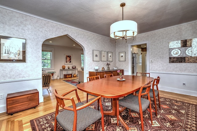 166 Roydon Rd, New Haven, CT 06511 - dining space with arched walkways, crown molding, light wood finished floors, and a textured ceiling