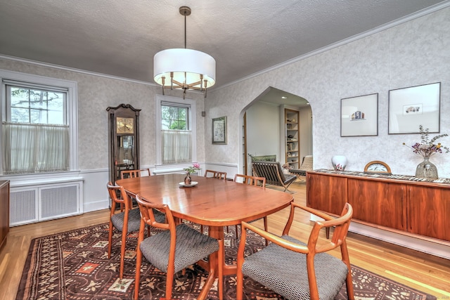 166 Roydon Rd, New Haven, CT 06511 - dining space with radiator, ornamental molding, wood finished floors, arched walkways, and wallpapered walls