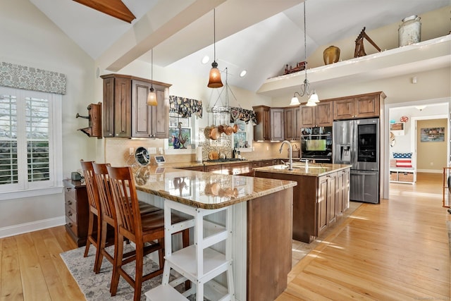 1 Shady Knls, Danbury, CT 06811 - kitchen featuring stainless steel fridge with ice dispenser, a kitchen island with sink, light stone countertops, decorative backsplash, and light wood-style floors