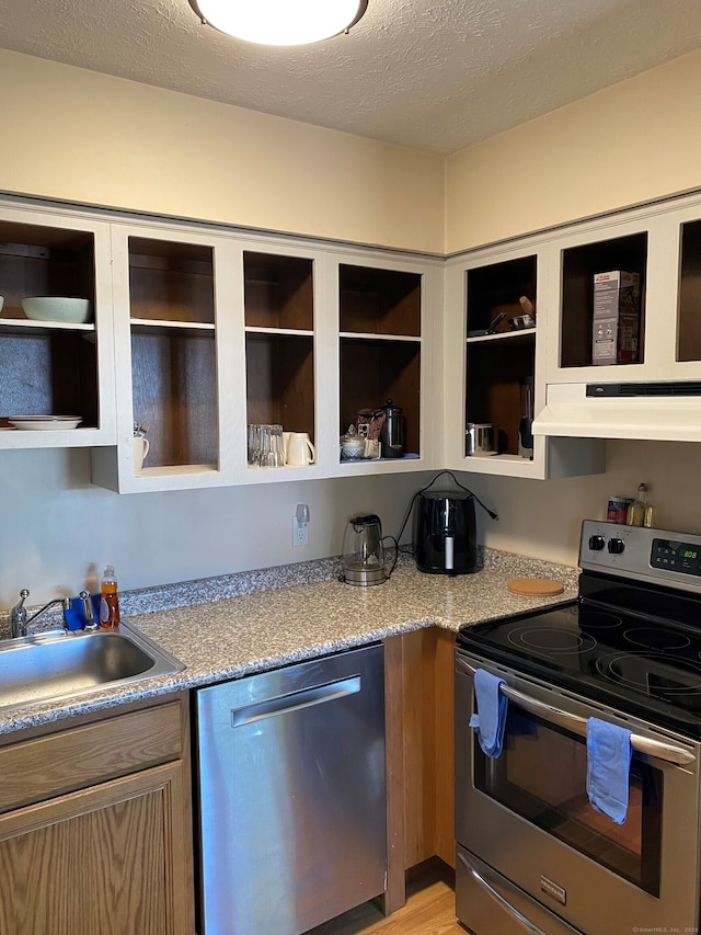 kitchen featuring appliances with stainless steel finishes, a sink, under cabinet range hood, light countertops, and a textured ceiling