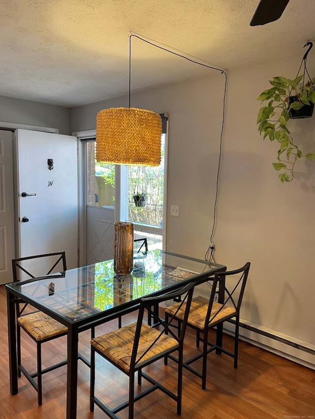 dining area with a textured ceiling, wood finished floors, and baseboards