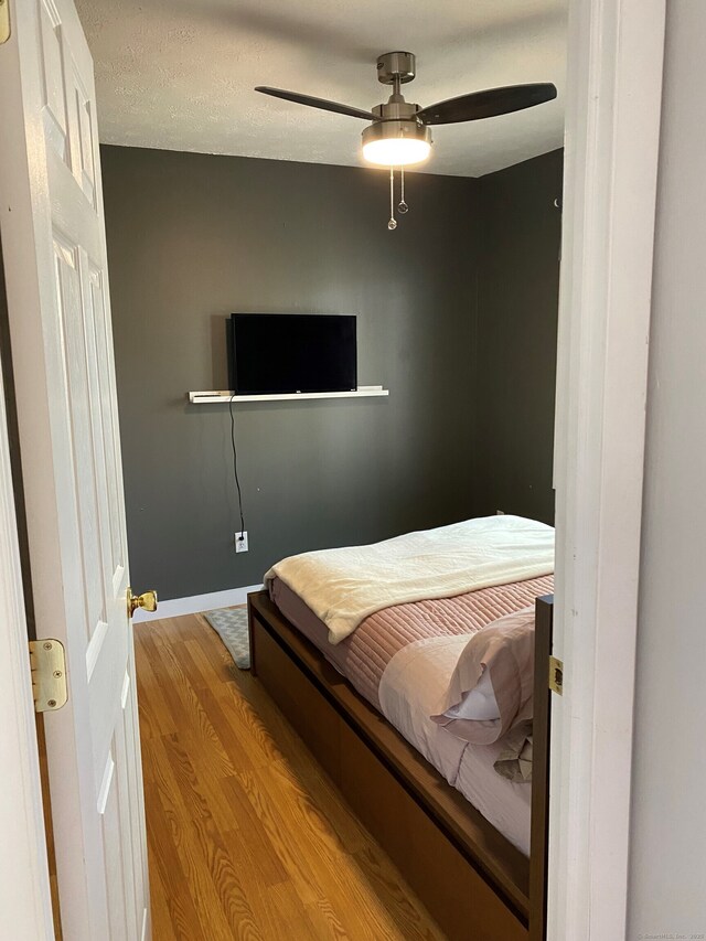 bedroom with wood finished floors, baseboards, and a ceiling fan