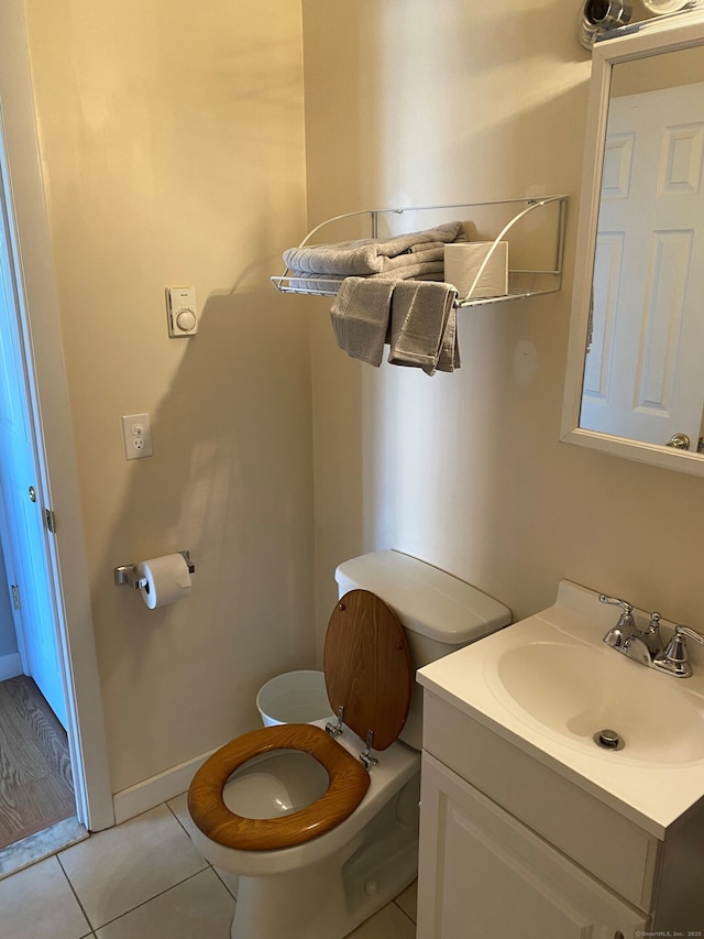 bathroom with toilet, tile patterned flooring, vanity, and baseboards