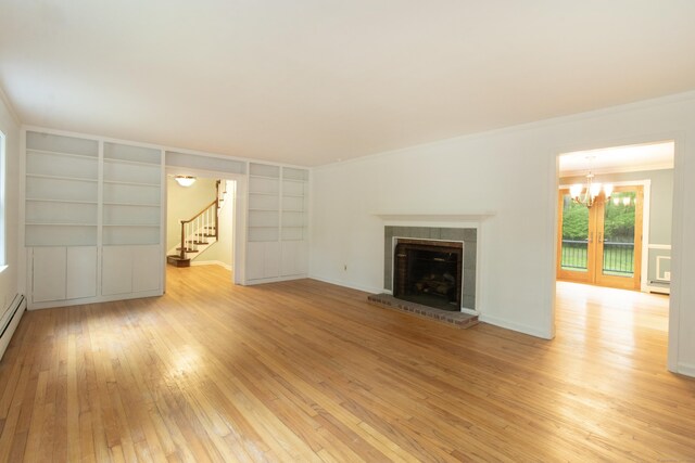 82 Whitethorn Dr, Guilford, CT 06437 - unfurnished living room with light wood-style floors, built in features, a chandelier, stairway, and a tile fireplace