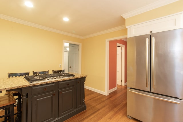 82 Whitethorn Dr, Guilford, CT 06437 - kitchen featuring appliances with stainless steel finishes, a kitchen breakfast bar, light wood-type flooring, crown molding, and baseboards