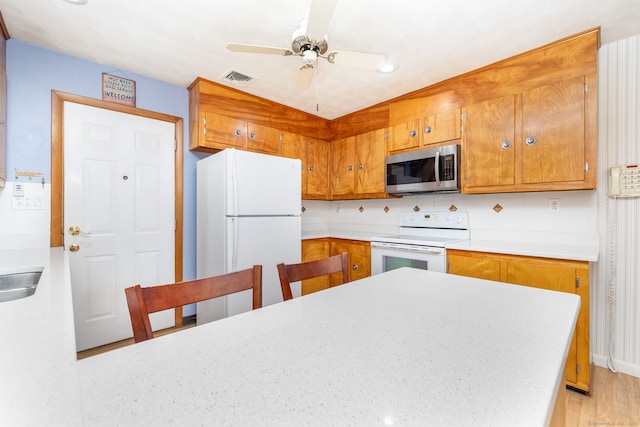 kitchen with white appliances, a ceiling fan, and brown cabinetry
