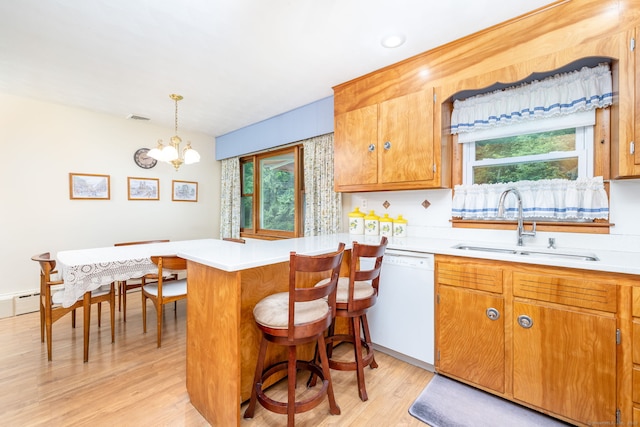 kitchen featuring white dishwasher, a sink, light wood-style floors, light countertops, and a chandelier