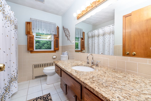 bathroom with radiator, tile patterned flooring, tile walls, toilet, and vanity