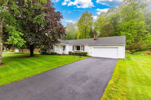 view of front of home with an attached garage, driveway, a front yard, and a chimney